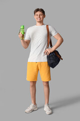 Sticker - Young man with sports bag and bottle of water on grey background