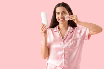 Sticker - Beautiful young happy woman with cotton pad and bottle of micellar water on pink background