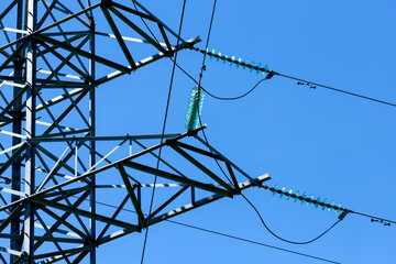 Wall Mural - High voltage line pole against blue sky with sunlight. Close up view.