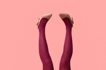 Poster - Legs of young woman in tights and heeled shoes on pink background