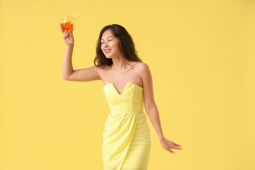 Sticker - Young Asian woman with aperol spritz cocktail on yellow background