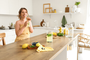 Poster - Young woman with tasty lemonade in kitchen