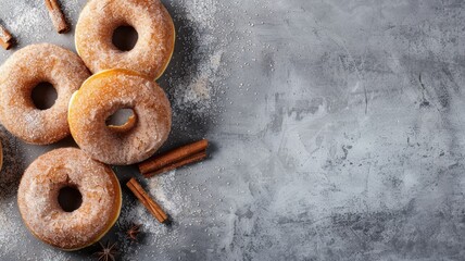 Wall Mural - Homemade cinnamon sugar donuts arranged with cinnamon sticks on a rustic background.