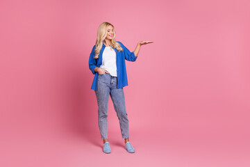 Poster - Full length photo of adorable lovely woman wear blue shirt showing arm empty space isolated pink color background