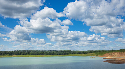 A beautiful blue lake with a few clouds in the sky