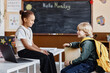 © Seventyfour - Side view of two diverse smiling kids communicating on break against blackboard on wall in classroom, copy space