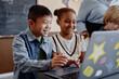© Seventyfour - Two happy multiethnic kids of primary school using laptop together having fun in lesson at school