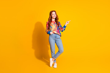 Full size photo of pretty young girl look point empty space wear trendy colorful outfit isolated on orange color background