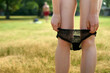© Connect Images - A young woman is changing panties in a park on a warm summer day