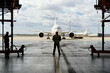© Connect Images - Ground crew member stands in an airplane hangar facing a parked commercial aircraft with another aircraft visible in the background.