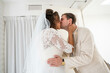 © Connect Images - Bride and groom share a passionate kiss on their wedding day, with the groom in a beige suit and the bride wearing a white lace gown and veil.