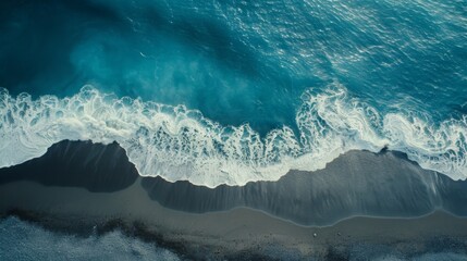 Aerial drone view or top view perspective photography of a beautiful transparent clear sea or ocean waves and foam splashing on the dark navy blue sand beach 