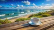 © Caitlin - A solitary coffee cup sits on a rustic wooden table, amidst a serene outdoor setting with a breathtaking sea view backdrop.