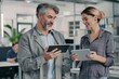 © MheeP - A man and woman discuss a plan using a tablet, showcasing teamwork and communication in the workplace.