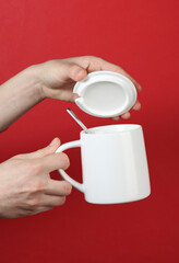 Wall Mural - Hands holding white ceramic cup with lid on red background