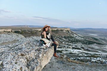 Wall Mural - Woman contemplating the vast valley below from a cliff's edge with majestic mountain backdrop