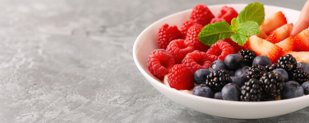 A white plate with a variety of berries and a sprig of mint