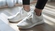 © pkproject - Comfortable white athletic sneakers on hardwood floor with sunlight