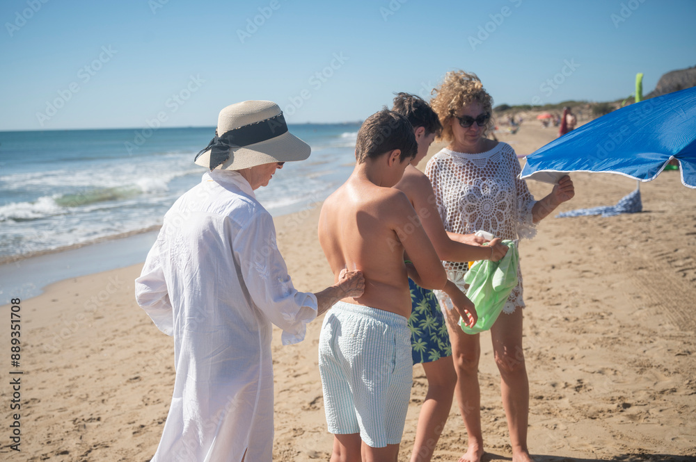 Grandmother applying sunscreen to grandson on family beach day Stock ...