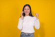 © amnaj - Young woman is talking on her phone and celebrating with a smile, suggesting she received good news or achieved a goal