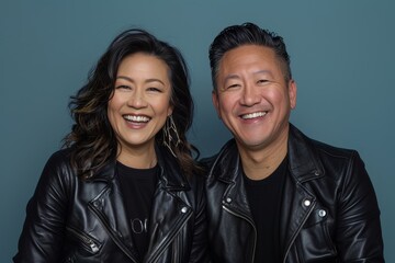 Wall Mural - Portrait of a joyful asian couple in their 40s sporting a classic leather jacket isolated in solid color backdrop