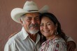 © CogniLens - Portrait of a blissful latino couple in their 50s wearing a rugged cowboy hat in solid color backdrop