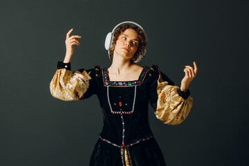 Wall Mural - Portrait of a young aristocratic woman with headphones on her head and dressed in a medieval dress listens classical music