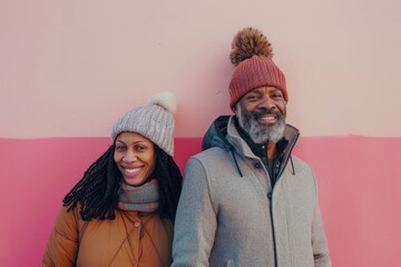 Wall Mural - Portrait of a satisfied multicultural couple in their 40s donning a warm wool beanie isolated in solid pastel color wall