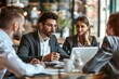 © Alina - Diverse businesspeople sitting at office desk discussing business project together