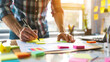 © sergign - A person actively designs and plans using colorful post-its at a bright workspace, embodying brainstorming, creativity, and thoughtful organization.