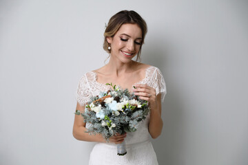 Wall Mural - Beautiful bride with winter wedding bouquet on light grey background