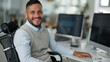 © Jane - Hispanic man sitting in a wheelchair working at a computer in a modern office