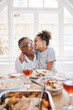 © Oostendorp/peopleimages.com - Home, grandfather and girl with kiss for dinner on thanksgiving, gathering and reunion. People, kid and happy or smile with food in table for memories, fun and love with support for care and bonding