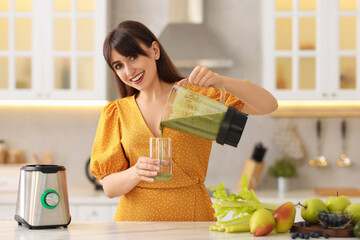 Sticker - Young woman pouring fresh smoothie from blender cup into glass at white marble table in kitchen