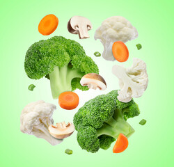 Wall Mural - Broccoli, cauliflower, cut mushrooms, carrot and spring onion in air on green gradient background