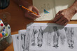 © DragonImages - Top view of designer drawing in album, he working over new fashion collection