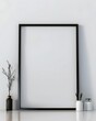 © Abdul - A mockup of an empty black frame on the wall, leaning against a white desk with a vase and pen holder.