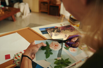 Designer cutting flowers from pictures for his fashion collage while working in workshop