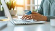 © Anutha - E-commerce concept with a hand holding credit card, laptop screen displaying shopping website, clean workspace, modern technology