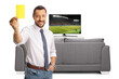 © Ljupco Smokovski - Businessman showing a yellow card in front of tv screen and smiling