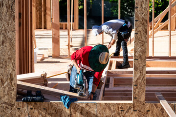 Wall Mural - Construction work crew building a new house in a residential neighborhood, wood framing started, sunny summer construction season
