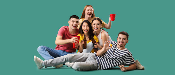 Wall Mural - Group of young friends with beer and ball on green background