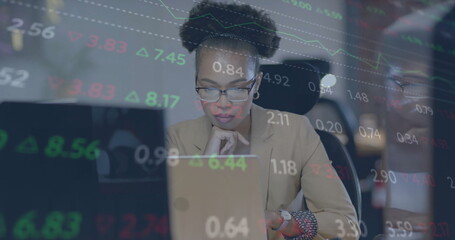 Poster - Image of financial data over african american businesswoman using laptop at office desk