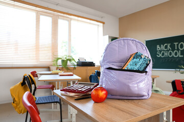 Wall Mural - Lilac backpack with pencil case and apple on desk in classroom