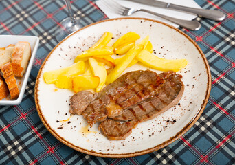 Canvas Print - Roasted beef Ternera con patata with potatoes fries on a ceramic plate cooked in a cafe