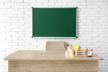 Wall Mural - Apple, books, alarm clock and stationery on teacher's desk in classroom. Back to school concept