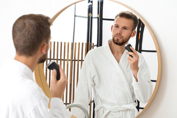 Sticker - Handsome young man trimming his beard near mirror in bathroom