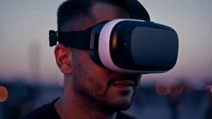 Fototapete - A man wearing a VR headset stands outside at sunset, his eyes closed as he experiences virtual reality.