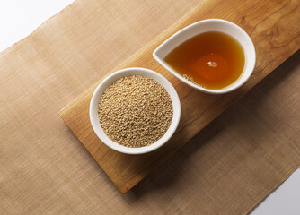 Wall Mural - Top angle view of stacked dried sesame seeds on bowl with sesame oil on another bowl, South Korea
