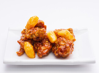 Close up of Chicken Gangjeong(Deep-fried and Braised Chicken) with bar rice cake on white dish and white floor, South Korea
